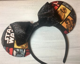 Puede incluir: Diadema negra con orejas temáticas de Star Wars. Las orejas están cubiertas con una tela de estilo cómic con imágenes de personajes y las palabras "STAR WARS". Un gran lazo negro brillante se encuentra entre las orejas.