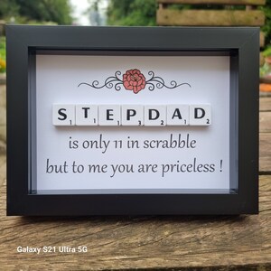 May include: A framed print with a red flower design and the word "STEPDAD" spelled out in Scrabble tiles. The text below reads "is only 11 in scrabble but to me you are priceless!"