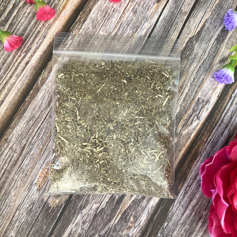 May include: A clear plastic bag filled with dried green herbs. The bag is sitting on a wooden surface.