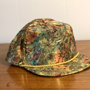May include: A gold floral patterned baseball cap with a yellow rope trim.