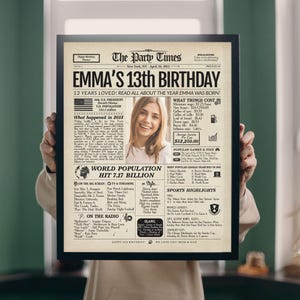 May include: A framed newspaper print titled "The Party Times" celebrating "Emma's 13th Birthday." The print includes a photo, headlines, and information about the year 2013, such as the U.S. President, population, and popular games.