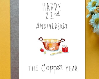 May include: A white greeting card with black text reading Happy 22nd Anniversary and The Copper Year. The illustration features a copper pot, a wooden spoon, a small jar of red jam, and a single strawberry with a small yellow flower.
