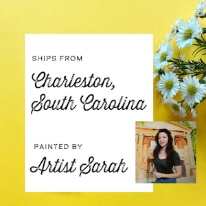 Op de afbeelding: Een witte rechthoekige kaart met zwarte tekst SHIPS FROM Charleston, South Carolina en PAINTED BY Artist Sarah. Een kleine ingevoegde foto toont een persoon met lang donker haar die een penseel vasthoudt voor een schilderij van een gebouw.