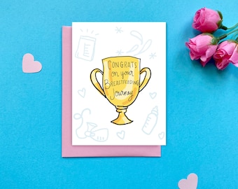May include: A white greeting card with a yellow trophy illustration featuring the text "CONGRATS on your BREASTFEEDING Journey" surrounded by light blue line drawings of baby items, placed on a pink envelope against a bright blue background.