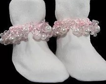 May include: Pair of white baby socks with pink and white pearl trim around the ankle.