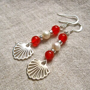 May include: A pair of silver earrings with red and white beads and a shell design.