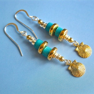May include: A pair of silver earrings with turquoise and gold beads and a gold seashell charm.