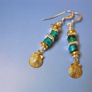 May include: A pair of silver earrings with green and gold beads and a gold seashell charm.