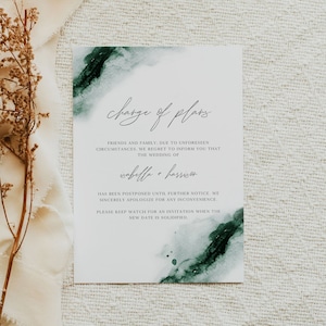 May include: A white card with the text "Change of Plans" and a watercolor design in shades of green. The card announces a wedding postponement for Isabella and Harrison. The background includes a neutral fabric and dried floral accents.