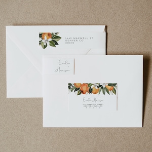 May include: A white envelope with a return address label featuring a floral design with orange blossoms and green leaves. The address reads "1642 Maxwell St, Denver CO 80210". The envelope is addressed to "Eulia Harrison" with the same address and a floral design.