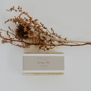May include: A bar of natural soap with a label that reads "DESERT BOHÈME organic soaps Rosemary + Aloe fine ingredients hand crafted net wt 115g"