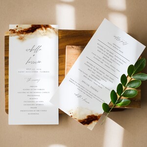 May include: A wedding ceremony program with a watercolor background and the names "Isabella & Harrison" printed in cursive. The program lists the order of events for the ceremony, including the prelude, seating of the families, lighting of the wedding candles, processional, readings, exchanging of vows, exchanging of rings, prayer, presentation of the couple, and recessional. The program also includes a list of the wedding party members, including the officiant, mother of the bride, father of the bride, maid of honor, bridesmaids, flower girl, mother of the groom, father of the groom, best man, groomsmen, ring bearer, and special thanks.