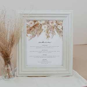 以下が含まれることがあります： 水彩画の花柄が描かれた白い額縁のメニュー。メニューには、前菜、アンティパスト、メインディッシュ、デザートが記載されています。テキストは次のとおりです。「menu」、「appetizer」、「pan seared scallops showers with citrus glass fried house made」、「local hibh leer and bleu cheese salad with house made bacon」、「antipasti」、「entree」、「grilled beef medallion with red wine mushroom reduction sauce」、「dessert」、「ウェディングケーキ」、「チーズケーキと新鮮なベリー」、「コーヒーと紅茶」。