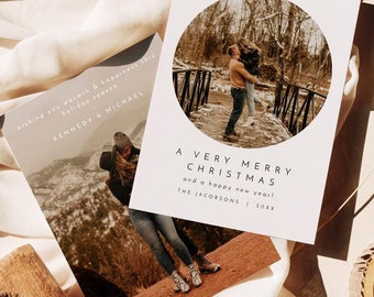Könnte beinhalten: Eine weiße Weihnachtskarte mit einem runden Ausschnitt, der ein Paar auf einer Brücke zeigt. Der Text lautet "A Very Merry Christmas and a happy new year! The Jacobsons 20XX".