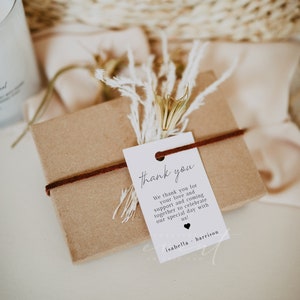 May include: A white thank you tag with black text that reads "thank you" and "We thank you for your love and support and coming together to celebrate our special day with us!"  The tag is tied with a brown ribbon to a small brown gift box. The tag also includes the names "isabella + harrison".