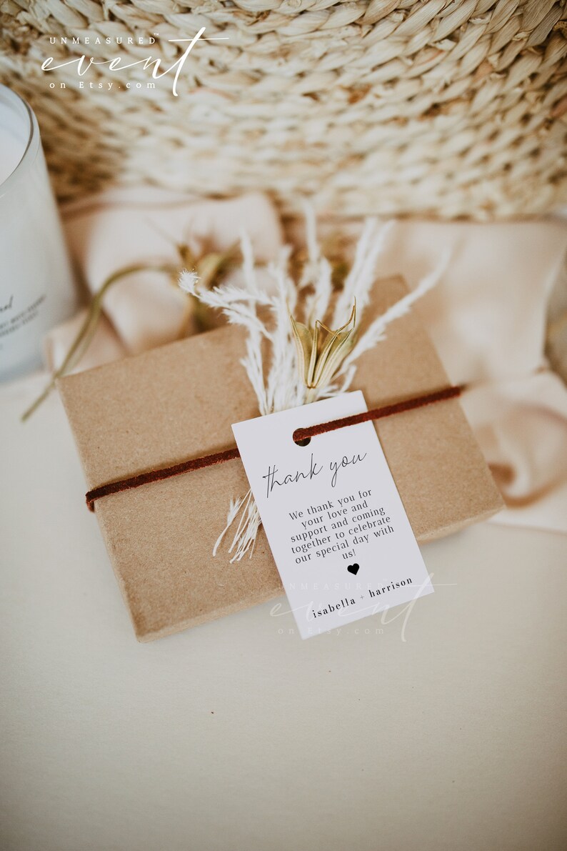 May include: A white thank you tag with black text that reads "thank you" and "We thank you for your love and support and coming together to celebrate our special day with us!"  The tag is tied with a brown ribbon to a small brown gift box. The tag also includes the names "isabella + harrison".