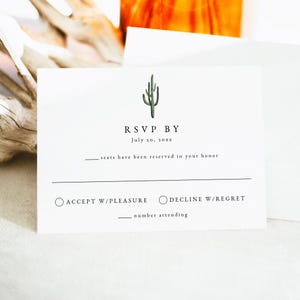 May include: White RSVP card with a green cactus illustration at the top. The text reads "RSVP BY July 20, 20xx". Includes options to accept or decline with space for the number attending. A simple and elegant design.