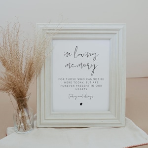 K&ouml;nnte beinhalten: Ein wei&szlig; gerahmtes Schild mit schwarzem Text, der "in loving memory" und "For those who cannot be here today, but are forever present in our hearts" und "today and always" mit einem kleinen schwarzen Herzen lautet.