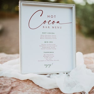 BLAIR Festive Red and Green Modern Christmas Hot Cocoa Bar Menu Sign Printable Template outdoors on a red rock with white cheesecloth