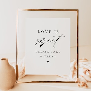 May include: A gold-framed sign with the text "Love is sweet. Please take a treat." and a small heart symbol.