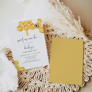 May include: A honeybee themed invitation for a first birthday party. The invitation features a watercolor illustration of a honeycomb with a bee and dripping honey. The text on the invitation reads "sweet as can bee" and "bailey's first bee-day!"  The invitation also includes the date, time, and location of the party.