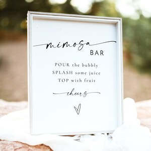 Pode incluir: Um sinal branco com texto preto que diz "Mimosa Bar". O sinal instrui os convidados a "Despejar o espumante, Adicionar um pouco de suco, Cobrir com fruta, Sa&uacute;de".