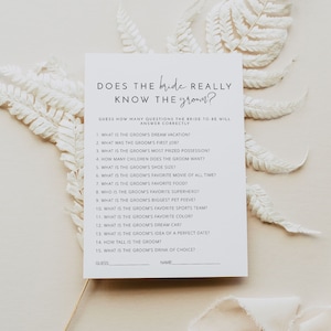 Peut inclure: Une carte de jeu de douche nuptiale imprimable avec le texte "La mariée connaît-elle vraiment le marié ?" et 15 questions sur le marié pour que les invités y répondent.