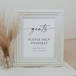 以下が含まれることがあります： 「gents please help yourself compliments of the newlyweds」と黒文字で書かれた白い額縁付きの看板です。