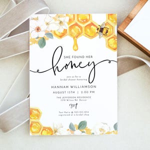 May include: A white bridal shower invitation with a watercolor illustration of a honeycomb dripping honey, white flowers, and a bee. The text reads "She found her honey" and includes details about the event, including the bride's name, date, time, and location. RSVP information is also included.