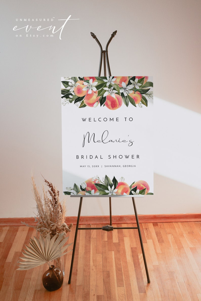May include: A white welcome sign with peach blossoms and fruit, announcing "Welcome to Melanie's Bridal Shower" with the date "May 15, 20XX" and location "Savannah, Georgia".