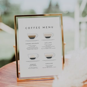 May include: A white sign with a gold frame lists a coffee menu with illustrations of different coffee drinks. The drinks listed are Caramel Macchiato, Cafe Latte, Espresso Con Panna, and Cappuccino. The sign is on a wooden table.