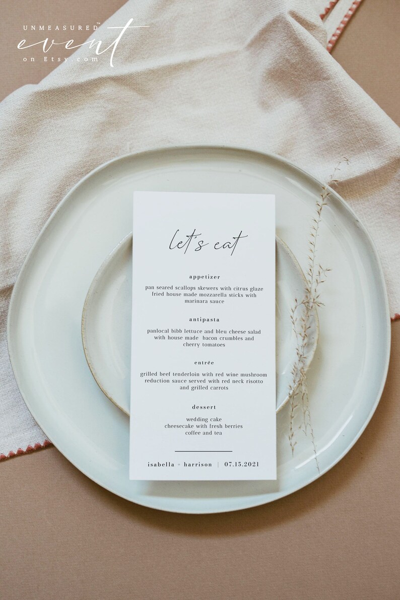 May include: A white card with black text on a white plate. The card has the words "let's eat" at the top and lists a wedding menu with appetizers, antipasta, entree, and dessert. The menu includes pan-seared scallops skewers with citrus glaze, panlocal bibb lettuce and bleu cheese salad, grilled beef tenderloin with red wine mushroom reduction sauce, wedding cake, and cheesecake with fresh berries. The bottom of the card has the names "isabella - harrison" and the date "07.15.2021".