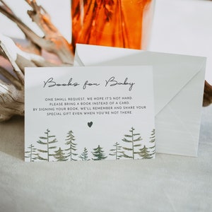 May include: A white card with a forest green border and a green heart in the center. The card reads "Books for Baby" and asks guests to bring a book instead of a card. The card is sitting on a white surface.