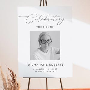 May include: A black and white photograph of a woman wearing glasses, set against a white background. The text "Celebrating the life of Wilma Jane Roberts 09.14.20XX - 12.19.20XX In loving memory" is printed below the photo.