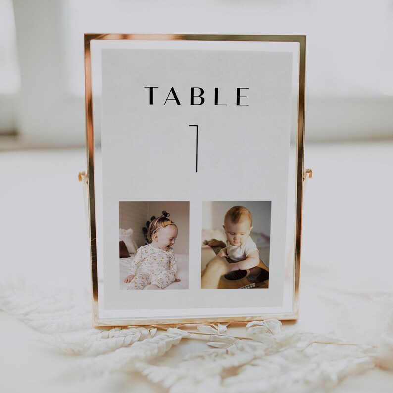 May include: Gold framed table number sign with the text "TABLE 1" and two photos of babies in the bottom half of the frame.