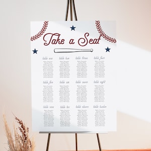May include: A white seating chart with a baseball theme. The chart has the words "Take a Seat" in a red and blue script font. The chart is divided into 12 sections, each with a table number and a list of names. The chart is decorated with red and blue baseball-themed graphics.