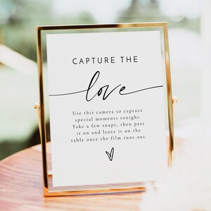 May include: A white sign in a gold frame with the text "CAPTURE THE love" and instructions to use the camera to capture special moments, take a few snaps, then pass it on and leave it on the table once the film runs out.
