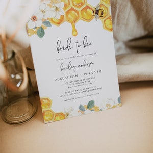 K&ouml;nnte beinhalten: Eine wei&szlig;e Einladung zu einer Bridal Shower mit einer Aquarell-Illustration eines Bienenstocks, tropfenden Honigs und einer Biene. Der Text lautet "bride to bee" und enth&auml;lt Details zur Veranstaltung, einschlie&szlig;lich Datum, Uhrzeit, Ort und RSVP-Informationen.