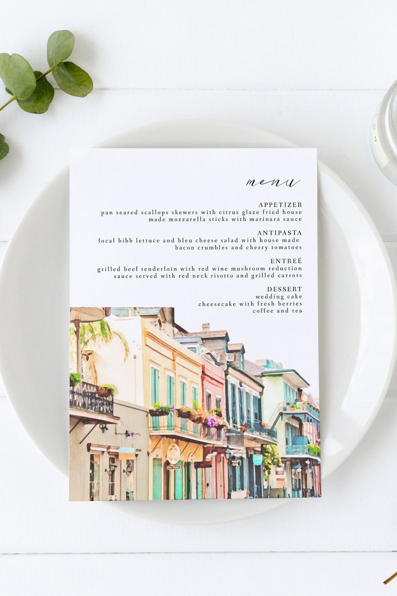 May include: A watercolor illustration of a New Orleans street scene with colorful buildings, balconies, and flowers. The menu features a selection of appetizers, antipasti, entrees, and desserts. The text reads: "menu", "appetizer", "pan seared scallops skewers with citrus glaze fried house made mozzarella sticks with marinara sauce", "antipasta", "local bibb lettuce and bleu cheese salad with house made bacon crumbles and cherry tomatoes", "entree", "grilled beef tenderloin with red wine mushroom reduction sauce served with red neck risotto and grilled carrots", "dessert", "wedding cake", "cheesecake with fresh berries", "coffee and tea".