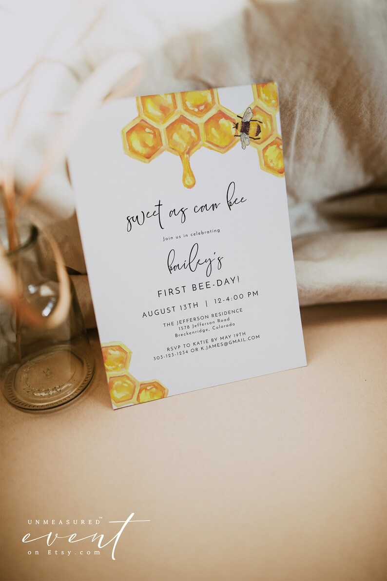 May include: A white invitation card with a watercolor illustration of a honeycomb and a bee. The text on the card reads "sweet as can bee" and "Join us in celebrating Bailey's First Bee-Day!" The invitation details the date, time, and location of the event. RSVP information is also included.