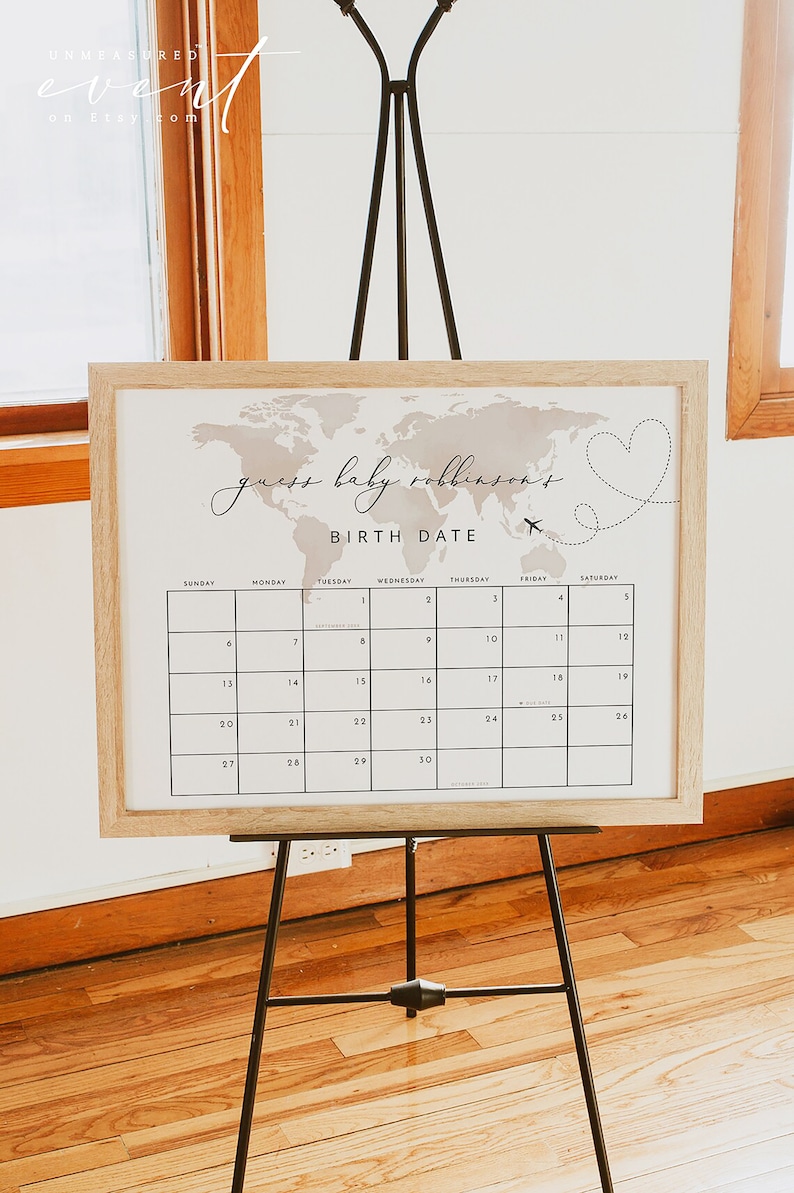 Peut inclure: Une affiche encadr&eacute;e blanche avec une carte du monde en arri&egrave;re-plan et un calendrier avec le texte "guess baby robinson's birth date" imprim&eacute; dessus. Le calendrier est pour le mois de septembre.