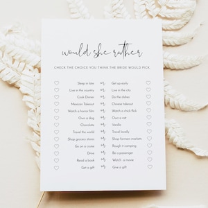 Op de afbeelding: Een printbaar bruidsdouchespel met de tekst "would she rather" en een lijst van 14 vragen met twee keuzes per vraag. De keuzes worden gepresenteerd in een zwart-wit ontwerp met een hartje naast elke keuze.