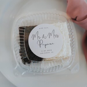 May include: A clear plastic container with a white and brown dessert inside. A white circle sticker with black text reads "with love, Mr. & Mrs. Papana 11.03.2019 SAN DIEGO, CA"