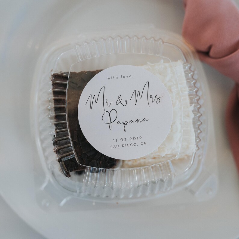 May include: A clear plastic container with a white and brown dessert inside. A white circle sticker with black text reads "with love, Mr. & Mrs. Papana 11.03.2019 SAN DIEGO, CA"