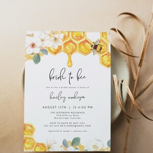 K&ouml;nnte beinhalten: Eine wei&szlig;e Karte mit einem Bienen- und Wabenmuster. Der Text auf der Karte lautet "bride to bee" und enth&auml;lt Details f&uuml;r eine Brautdusche zu Ehren von Hailey Anderson. Die Dusche findet am 13. August von 12:00 bis 16:00 Uhr in The Jefferson Residence, 1578 Jefferson Road, Breckenridge, Colorado statt. Bitte melde dich bis zum 19. Mai bei Katie unter 303-123-1234 oder k.james@gmail.com an. Das Paar ist bei Target und Amazon registriert.