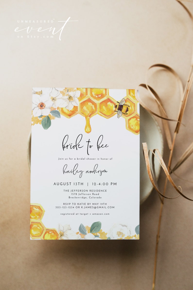 K&ouml;nnte beinhalten: Eine wei&szlig;e Karte mit einem Bienen- und Wabenmuster. Der Text auf der Karte lautet "bride to bee" und enth&auml;lt Details f&uuml;r eine Brautdusche zu Ehren von Hailey Anderson. Die Dusche findet am 13. August von 12:00 bis 16:00 Uhr in The Jefferson Residence, 1578 Jefferson Road, Breckenridge, Colorado statt. Bitte melde dich bis zum 19. Mai bei Katie unter 303-123-1234 oder k.james@gmail.com an. Das Paar ist bei Target und Amazon registriert.