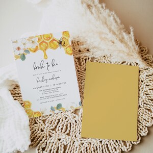 K&ouml;nnte beinhalten: Eine Einladung zu einer Bridal Shower mit einem Bienen- und Wabenmuster. Die Einladung lautet "Bride to Bee" und enth&auml;lt Datum, Uhrzeit und Ort der Veranstaltung. RSVP-Informationen sind ebenfalls enthalten.