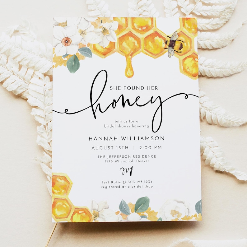 May include: A white bridal shower invitation with a watercolor illustration of a honeycomb dripping honey and a bee. The text reads "She found her honey" and includes details about the event, including the bride's name, date, time, and location. RSVP information is also included.