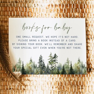May include: A white card with the text "books for baby" in green script. The card requests guests bring a book instead of a card. A watercolor forest scene is at the bottom. A feather rests on the woven background.