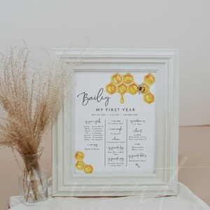 May include: A printable baby milestone chart with a honeycomb and bee design. The chart is titled "Bailey My First Year" and includes details like first smile, first tooth, first roll, first crawl, first stand, first clap, first word, first food, first steps, first time saying "mama" and "dada", favorite toys, favorite books, favorite songs, and favorite bedtime routine. The chart is perfect for documenting a baby's first year.